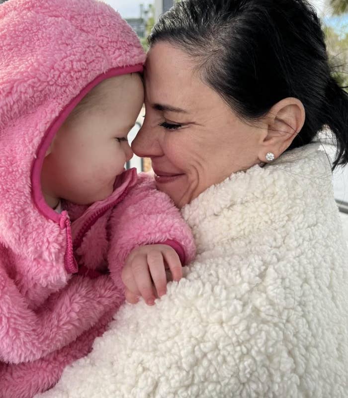 Voksen og baby i koselige, fluffy jakker koser seg til nese, og deler et ømt øyeblikk