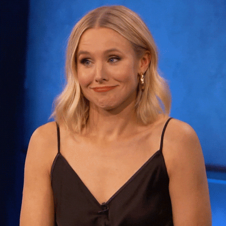 Person med hår i mellomlengden smiler tafatt i en svart camisol topp på scenen eller på et arrangement