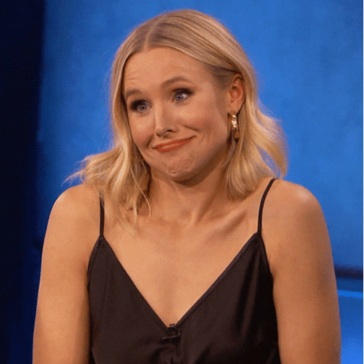 Person med hårlengde hår gir et lekent, trukkete uttrykk mens du har på seg en ermeløs svart topp