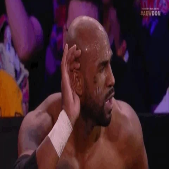 Wrestler på scenen poserer med hånden bak øret, og antyder å lytte til publikums reaksjon under en kamp