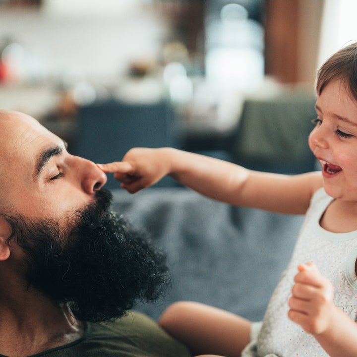 Foreldre som hviler med lukkede øyne, mens barnet lekent berører nesen, både smilende og deler et gledelig øyeblikk