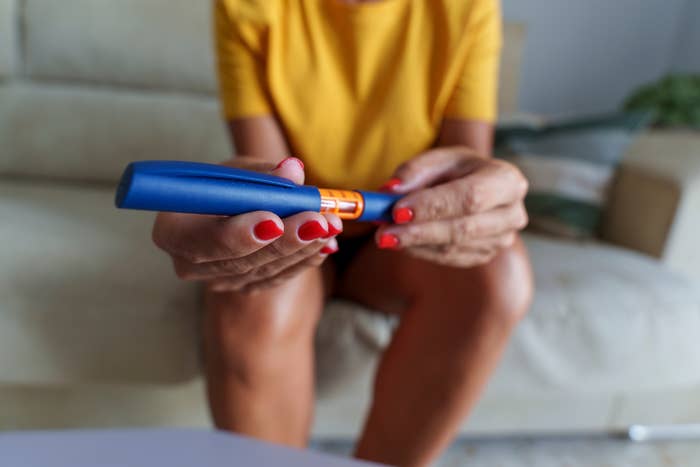 Personen som holder en insulinpenn mens du sitter på en sofa, fokuserer på pennen