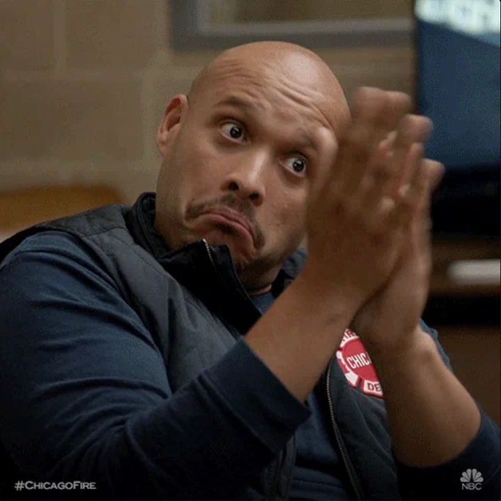 Person som klapper med et skeptisk uttrykk, iført en uformell skjorte og vest, hashtag og TV -show -logo i hjørnet