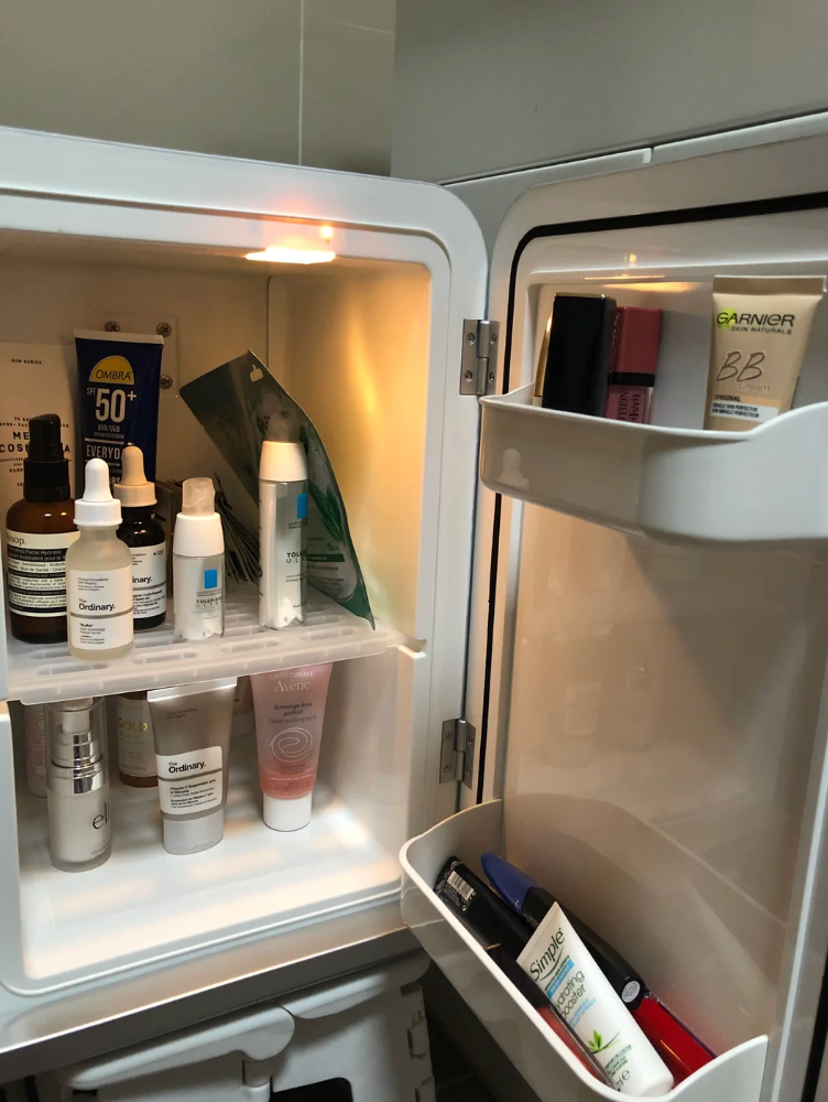 Et lite kjøleskap fylt med forskjellige hudpleieprodukter, inkludert flasker, rør og en ansiktsmaske