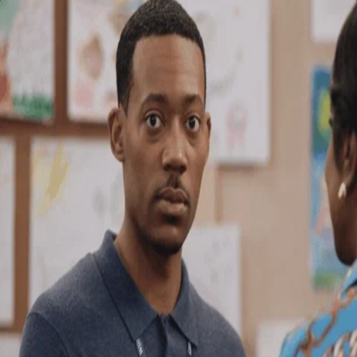 En person i en uformell polo-skjorte ser på noen utenfor kameraet i en setting med barnelegninger på veggen