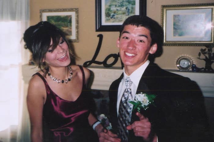 To personer i formell antrekk som smiler; Den ene har på seg en satengkjole med et halskjede, den andre en dress med en korsage, i et dekorert rom