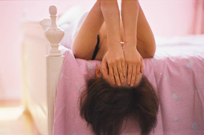 Person som ligger på sengen opp ned, dekker ansiktet med hendene, antyder avslapning eller ettertanke