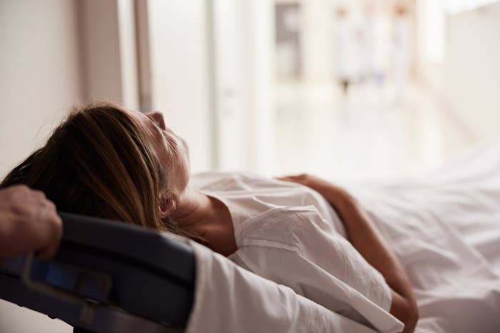 Person som ligger i en sykehusseng som blir dyttet ned en gang, noe som antyder omsorg eller legehjelp