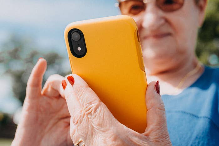 Eldre voksen som bruker en smarttelefon med fokus på hendene og telefonen, noe som antyder et øyeblikk av teknisk engasjement