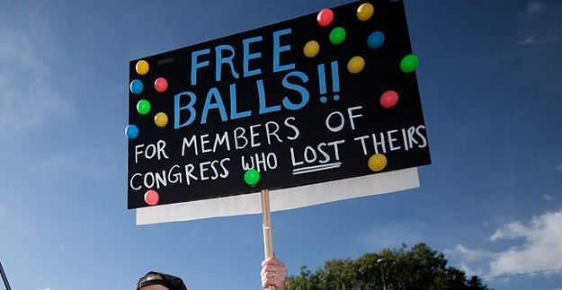 Personen holder et protestskilt som sier «GRATIS BALLER!! FOR KONGRESSMEDLEMMER SOM MISTET SINE," med fargerike baller festet