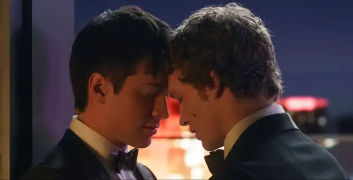 To personer i smoking deler et nært, intimt øyeblikk, mens de lener pannen forsiktig sammen