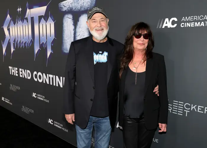 Rob Reiner og Michele Singer Reiner i uformelt antrekk på en rød løper. Mannen har på seg en grafisk T-skjorte med blazer; kvinnen sporter solbriller og et mørkt antrekk