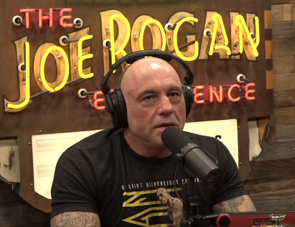 Person som har på seg et hodesett, snakker i en mikrofon foran skiltet Joe Rogan Experience