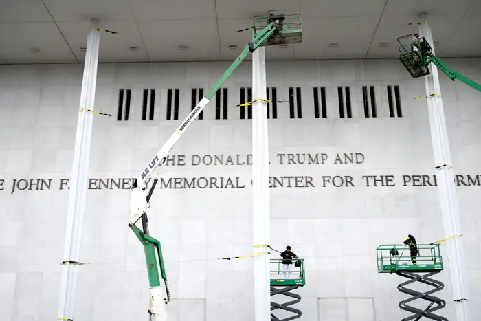 Arbeidere på heiser vedlikeholder utsiden av Kennedy Center, med synlig gravert tekst på fasaden