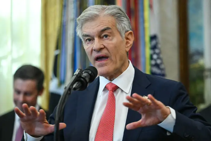 En person i dress som snakker lidenskapelig ved en mikrofon under en formell begivenhet