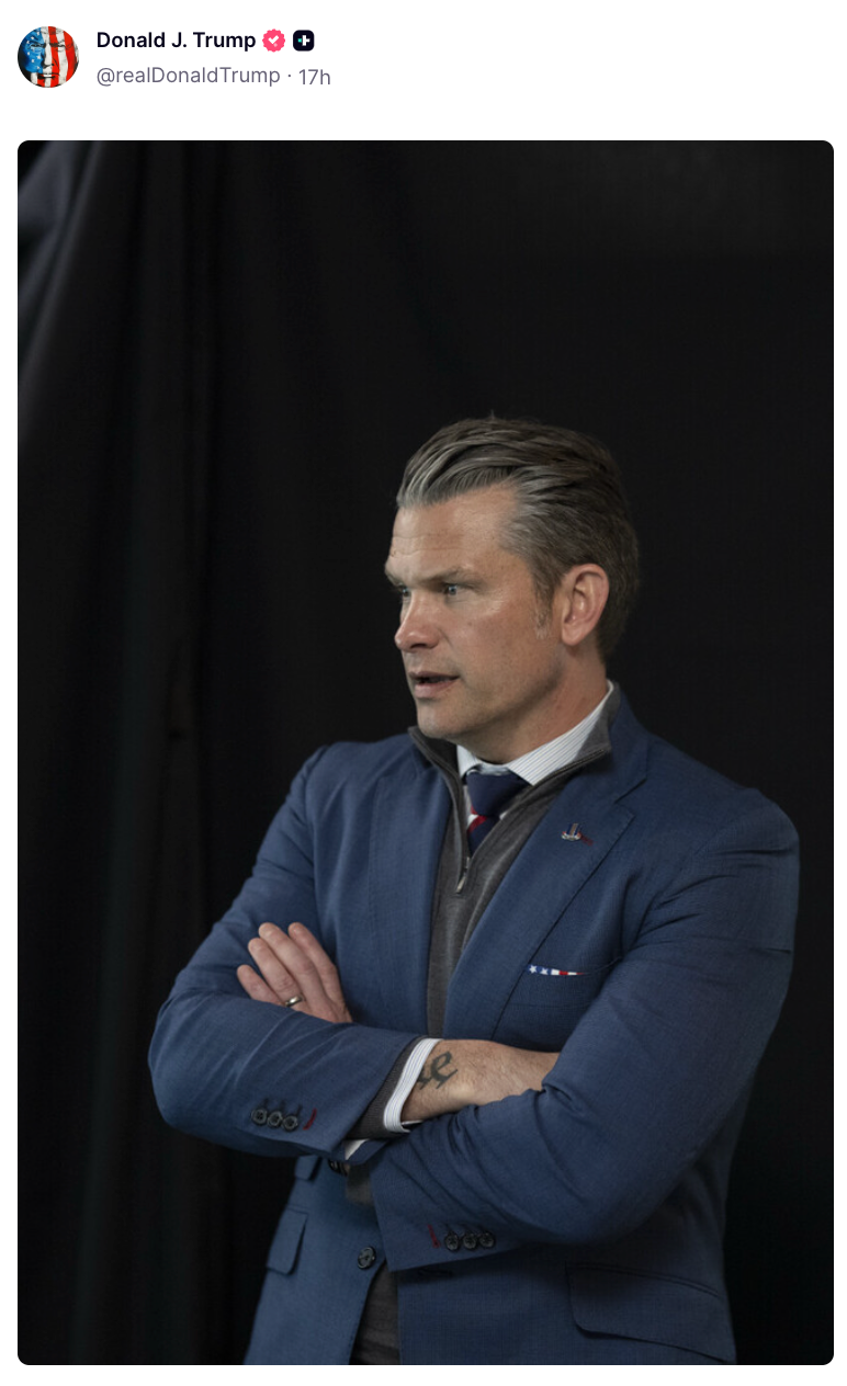 En person i dress med armene i kors mot en mørk bakgrunn