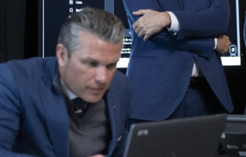 To menn i dress jobber intenst i et moderne kontormiljø, med fokus på en bærbar datamaskin