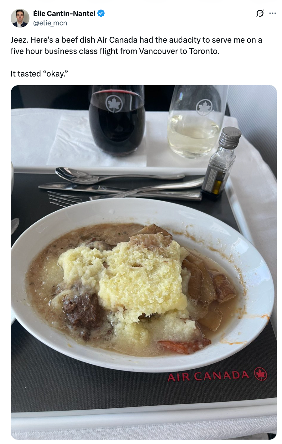 Biffrett med potetmos servert på et Air Canada-fly, med rødvin og vann på et brettbord