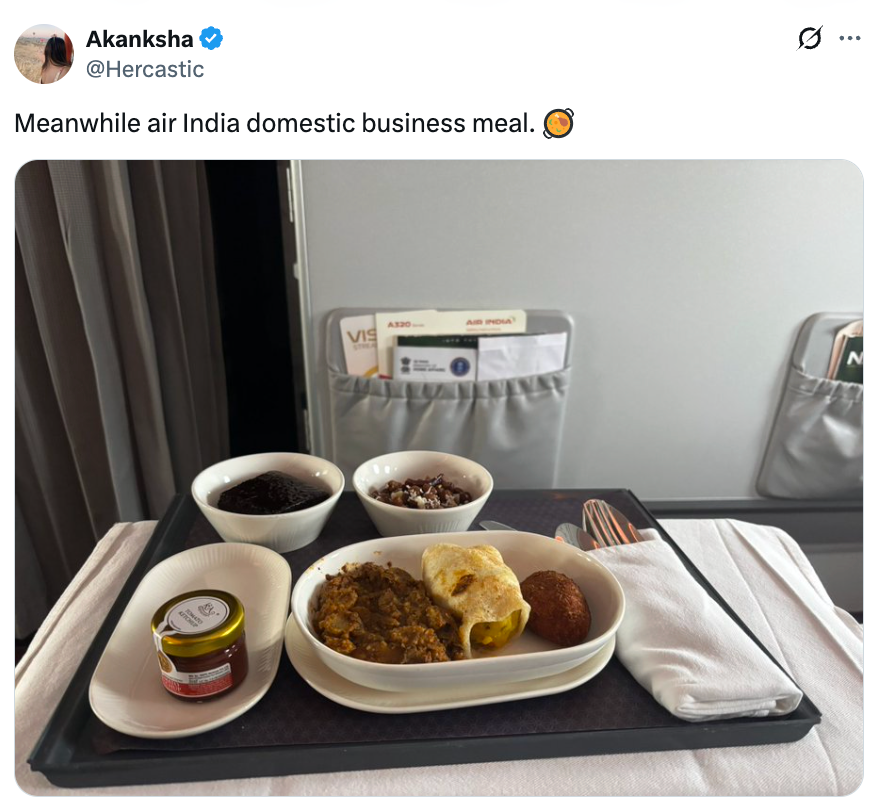 Flyselskapsmåltid med ris, karri, rundstykke og tilbehør på et brett. En liten krukke sees sammen med måltidet