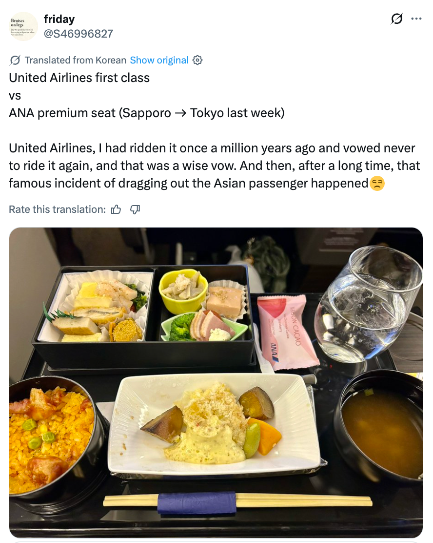 Måltidsbrett med diverse retter, inkludert ris, salat og fisk, servert på et flyselskaps førsteklasses sete