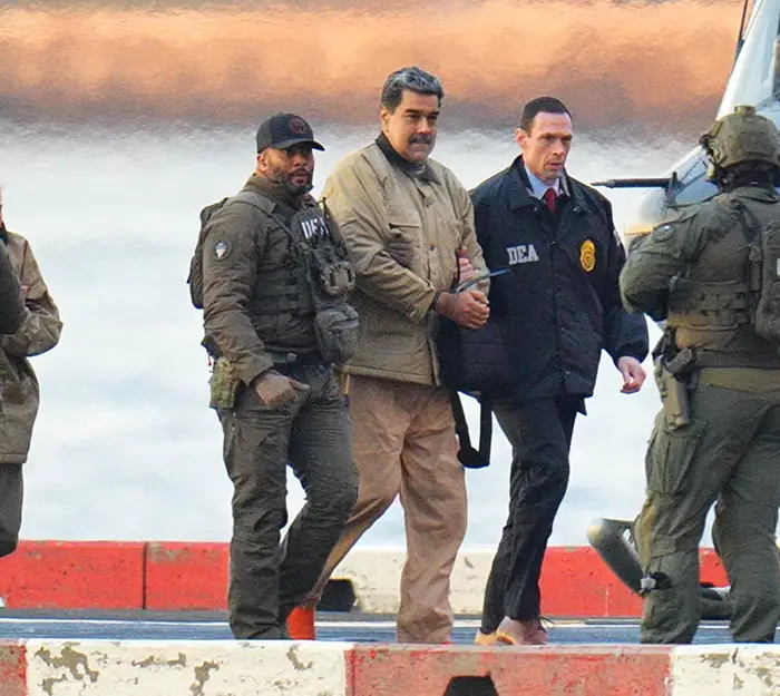 En gruppe politifolk som eskorterer en mann i håndjern nær et helikopter