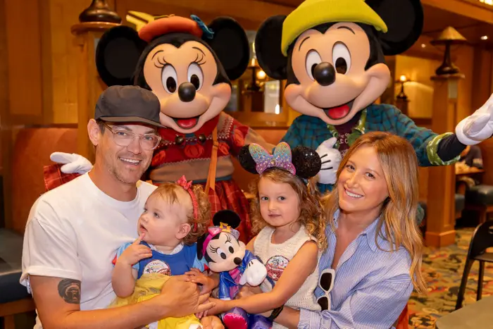 Ashley Tisdale og familien hennes poserer med Mikke og Minnie Mouse i Disneyland og holder suvenirer