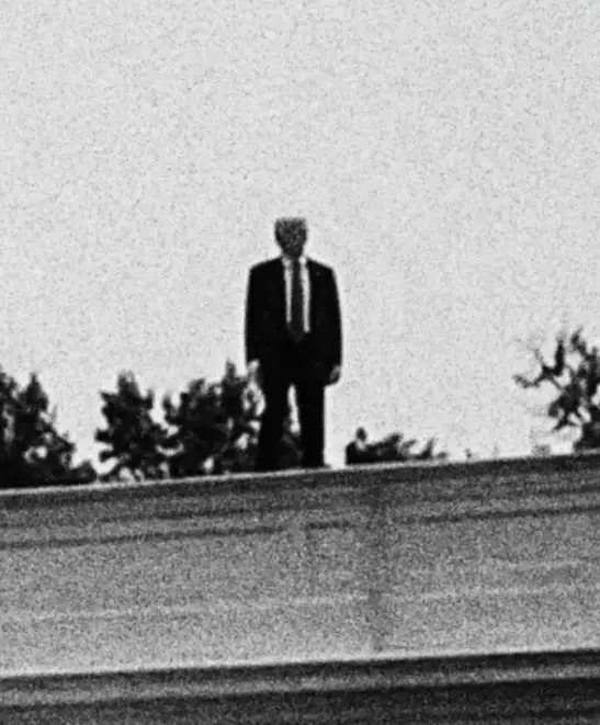 Et svart-hvitt-bilde viser en person som står på et hustak. Tweet-teksten lyder 