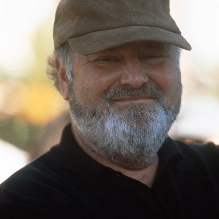 En mann med skjegg iført en caps og en uformell skjorte smiler til kameraet