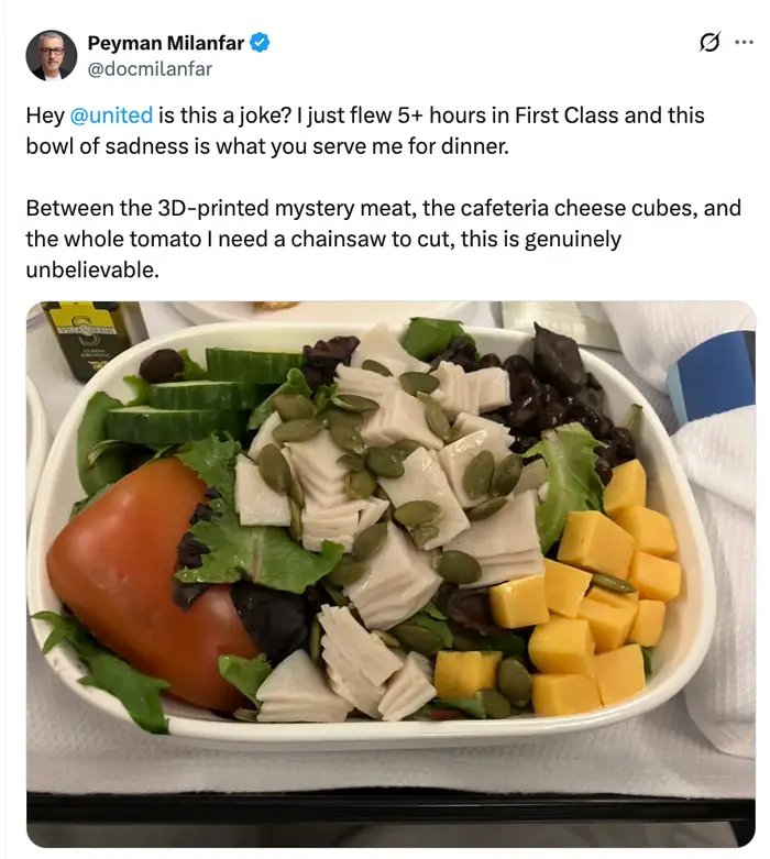 Salat med ost i terninger, frø, grønnsaker, oliven og skiver delikatessekjøtt, med en hel tomat, servert i et flyselskaps måltidsbrett