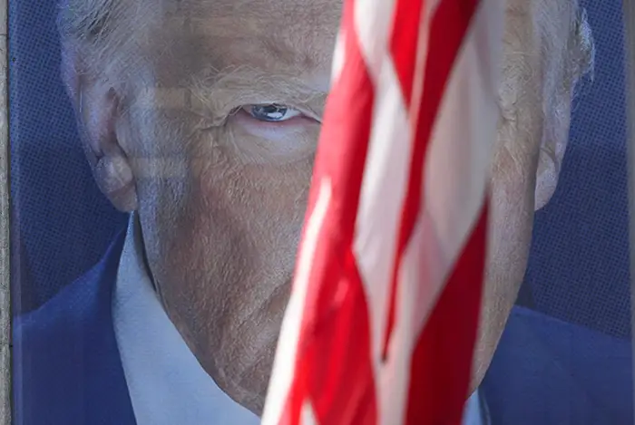 Delvis skjult av et flagg, ses et stort bilde av en persons intense blikk