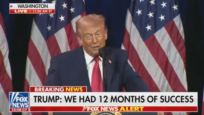 En person snakker ved et podium med flagg i bakgrunnen. Nyhetsoverskriften lyder: 