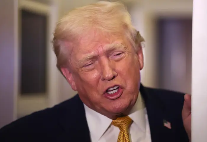 En person i dress og slips ser ut til å snakke lidenskapelig, med et alvorlig uttrykk, fanget innendørs