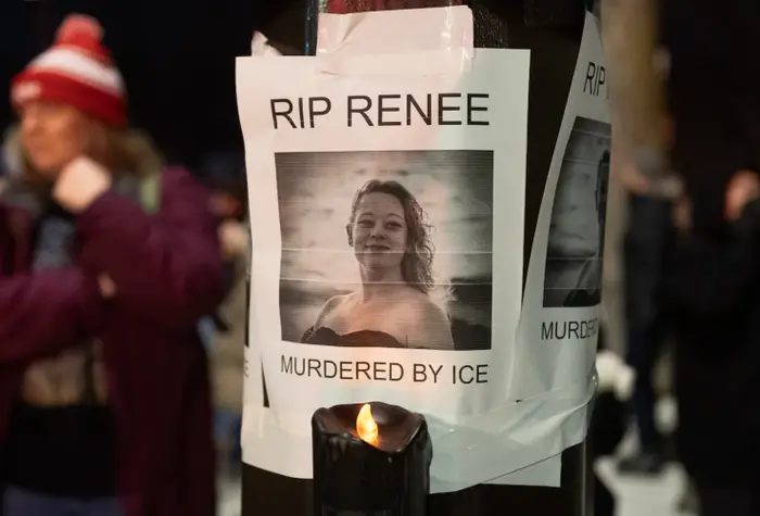 Minnesmerke for Renee med "RIP Renee" plakat på stang, omringet av folk på en våkenvakt. Skiltet over viser 
