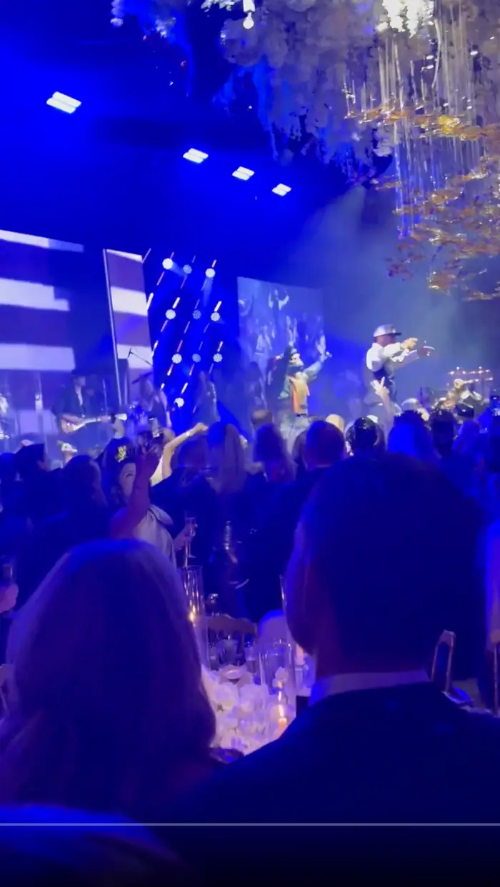 Folk nyter en livekonsert i et levende innendørslokale med scenelys og dekorasjoner