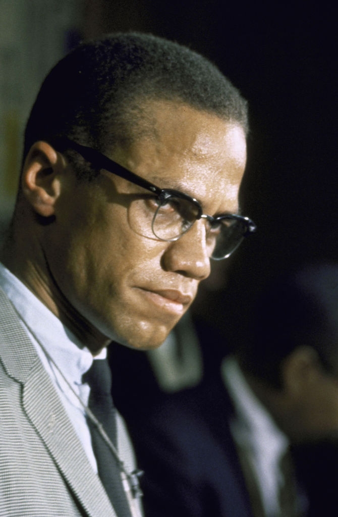 Mann i briller iført en formell dress og slips, ser ettertenksom ut, på et offentlig arrangement