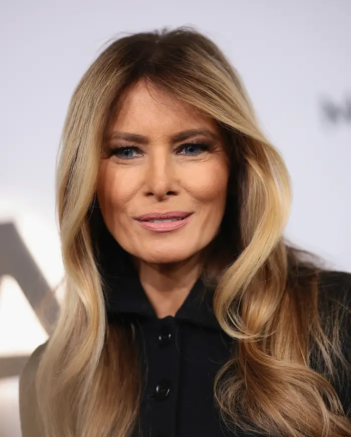 En person med langt hår og mørkt antrekk poserer for et bilde