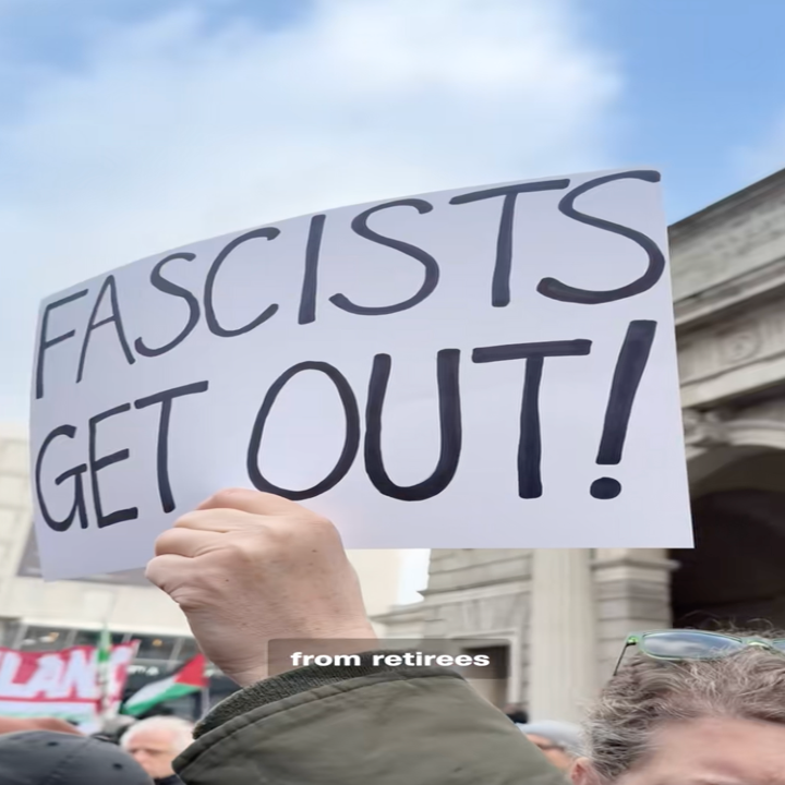 Demonstranten holder et skilt der det står "Fascists Get Out!" på en demonstrasjon, fanget foran en buegang