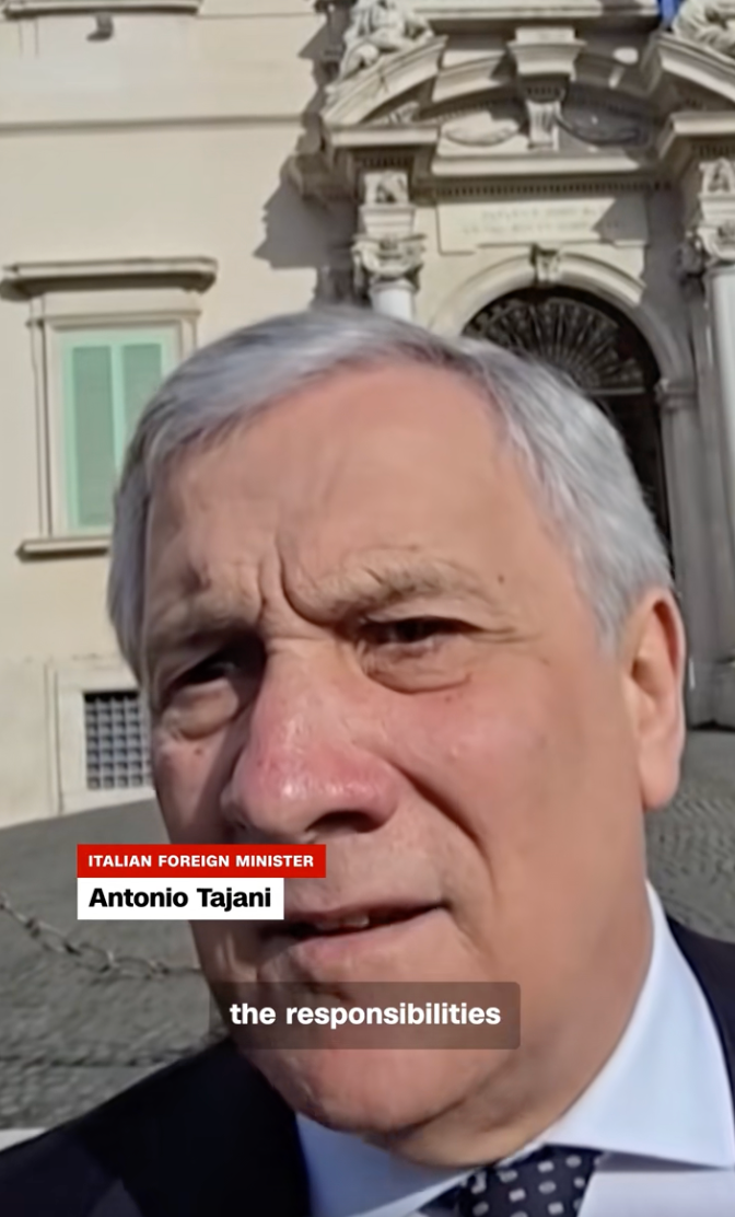 En mann som snakker utendørs; teksten lyder 