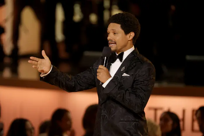 En person i en mønstret smoking gester mens han snakker i en mikrofon ved en formell begivenhet