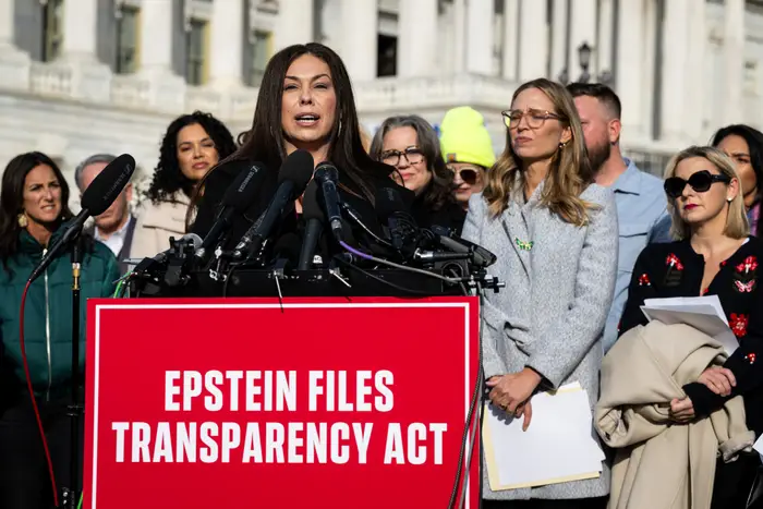 En gruppe mennesker står bak et podium med et skilt med teksten «Epstein Files Transparency Act»; foran en regjeringsbygning