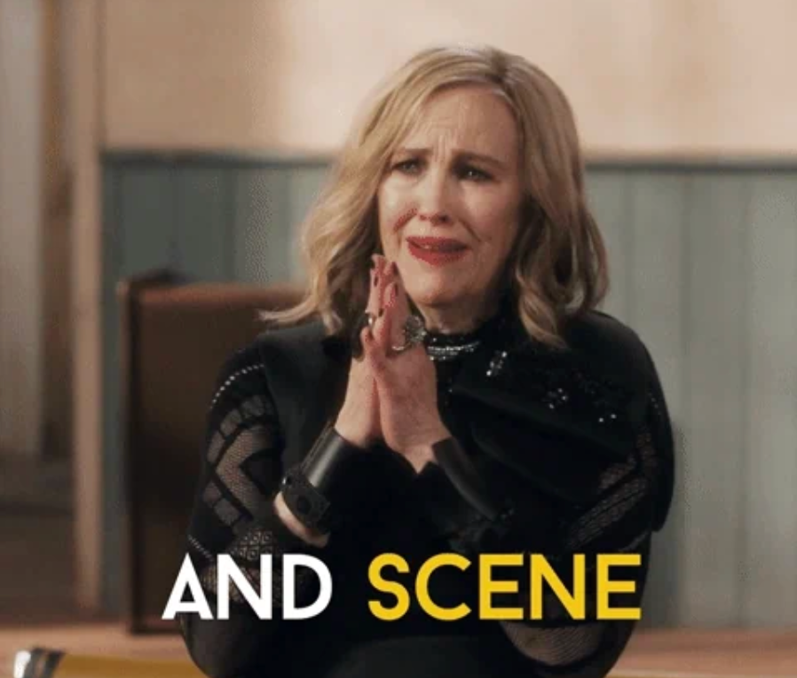 Person som spenner hendene med et lettet uttrykk, iført svart antrekk. Teksten lyder "OG SCENE."