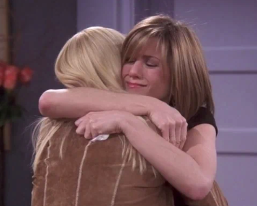 To kvinner omfavner varmt, en med rett hår. De fremstår som emosjonelle, formidler trøst og støtte i en personlig eller profesjonell sammenheng