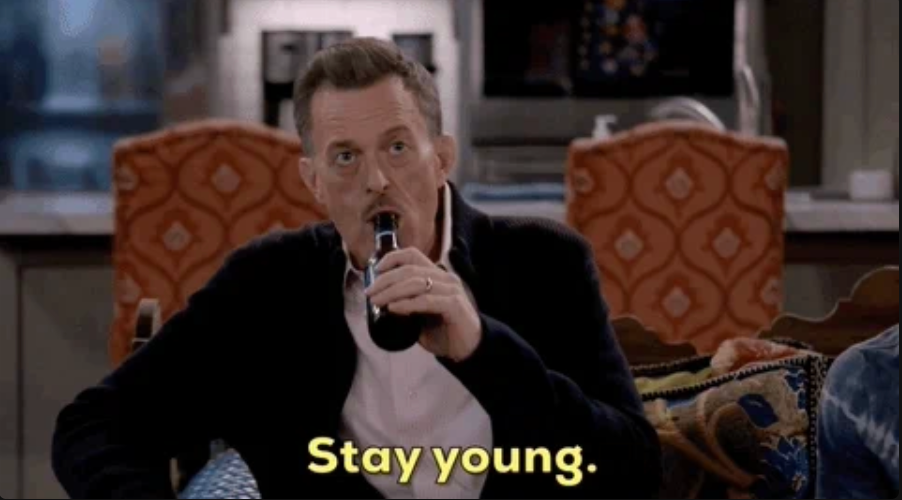 En person drikker av en flaske mens han sitter innendørs, sier «Forbli ung»; vises nederst