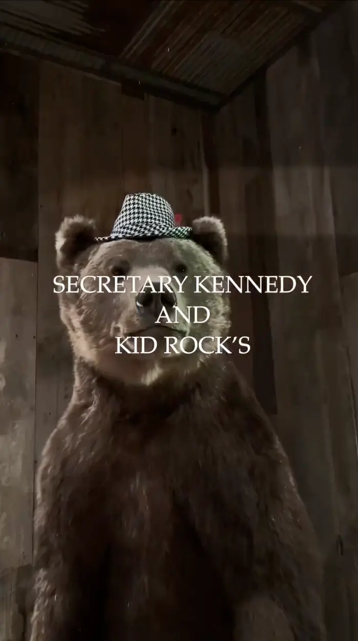 En bjørn statue iført en houndstooth hatt står innendørs; teksten lyder 