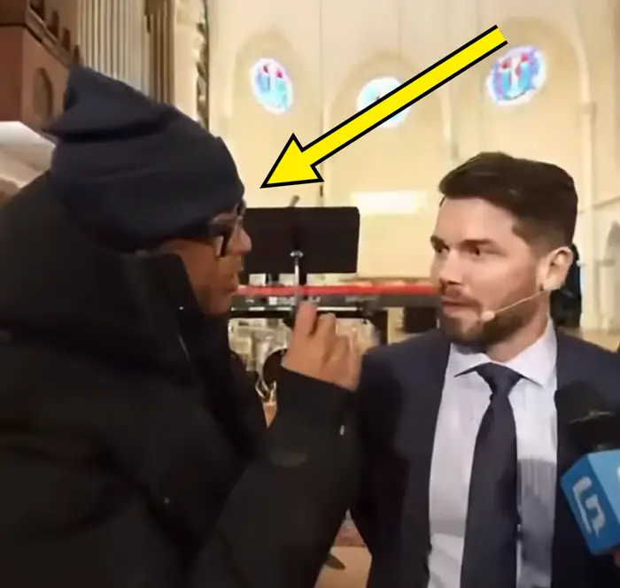 To personer har en samtale i en kirkelig setting, den ene intervjuer den andre. Intervjuobjektet har på seg dress og slips