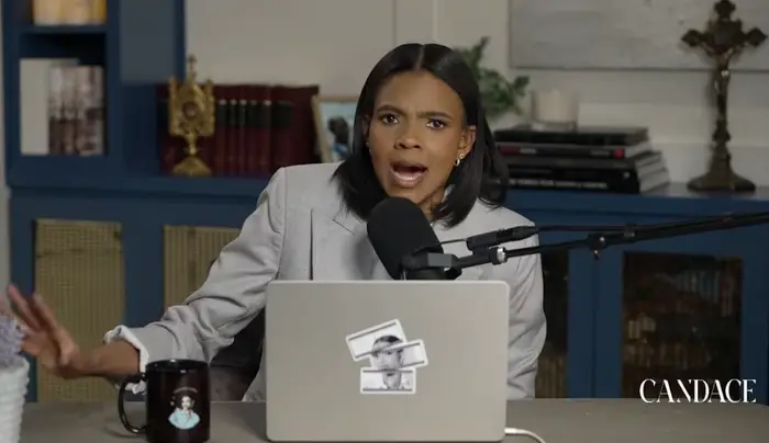 Person som snakker lidenskapelig inn i en mikrofon under et podcastopptak, gestikulerer med én hånd, i et studio med bøker