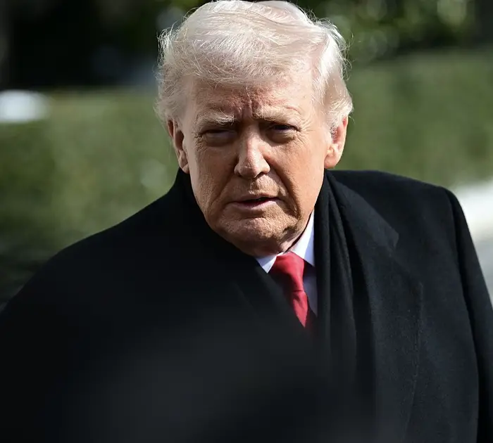 En person i dress og rødt slips er utendørs og fremstår som gjennomtenkt, i en nyhetssammenheng