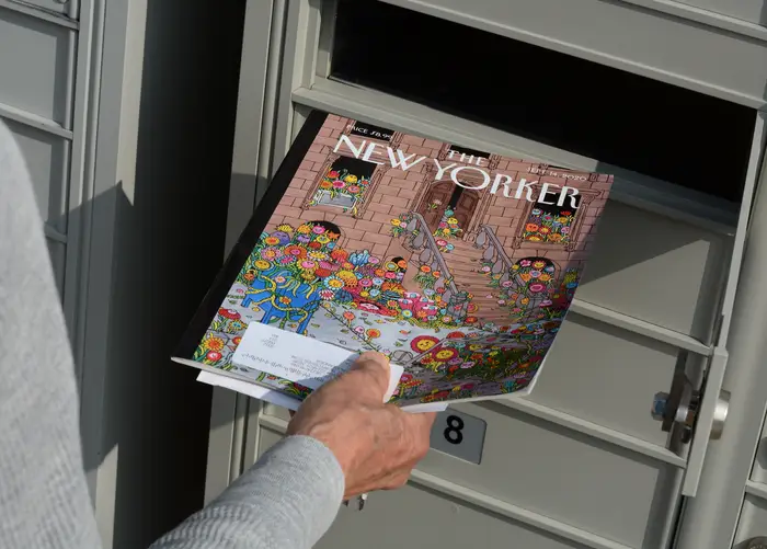 Person som henter magasinet New Yorker fra en postkasse. Omslaget har en illustrasjon med et blomstertema
