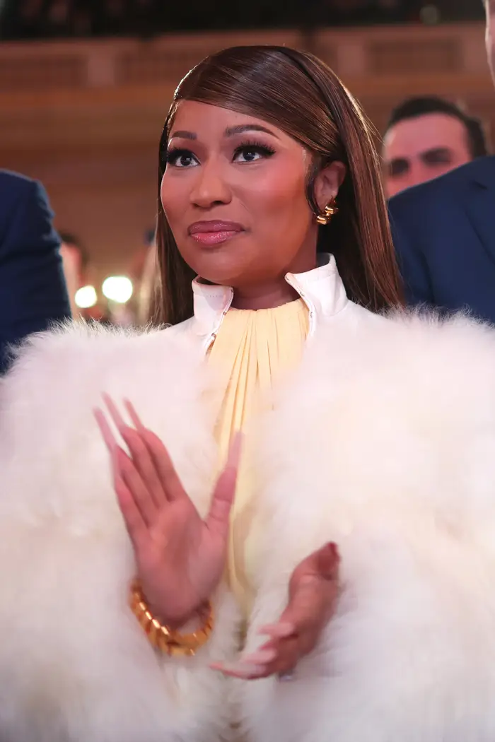 Kvinne i en elegant pels klapper på et arrangement, og utstråler eleganse med elegant frisyre og gullsmykker