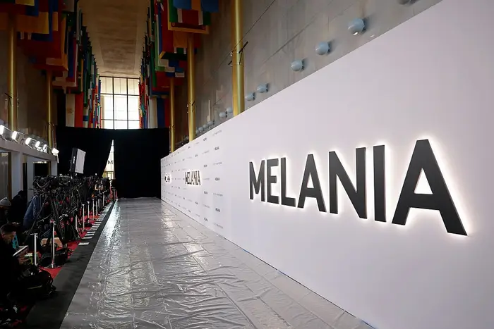 Tøm eventplass med "Melania" med store bokstaver på en vegg, foret med medieutstyr for et arrangement på den røde løperen